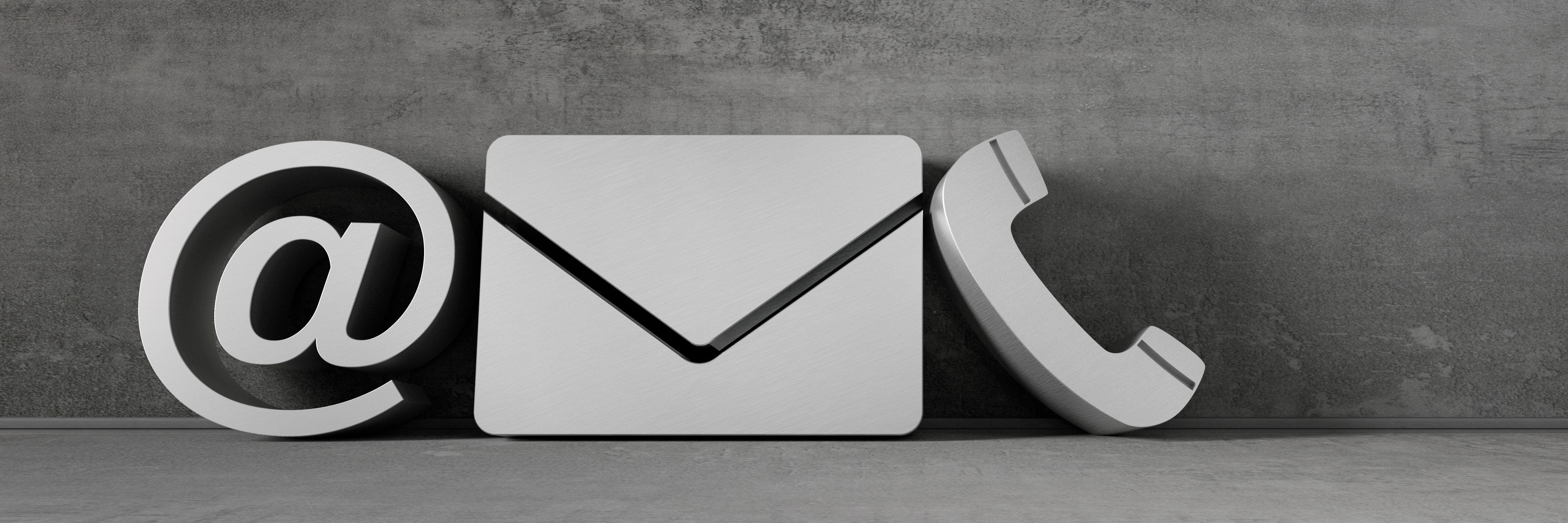Kommunikationssymbole @, Briefumschlaug und ein Telefonhörer vor einen grauen Betonwand
