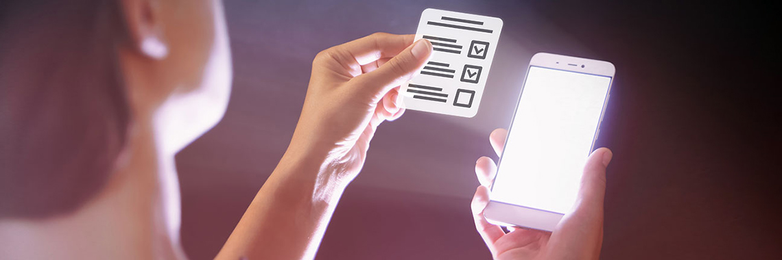 Symbolbild Digitalisierung von Verwaltungsleistungen - Person mit Smartphone und Formular in der Hand